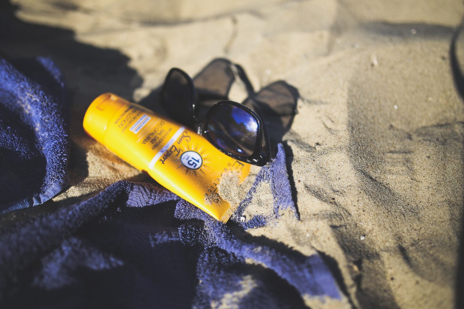 sunglasses and sunscreen on a towel on the beach