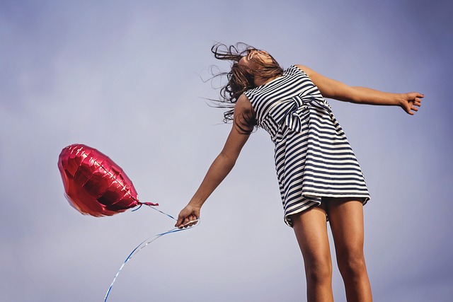 woman in striped dress holding a heart-shaped balloon