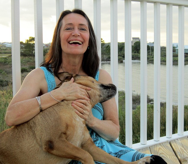 middle-aged woman cuddling her dog by a fence
