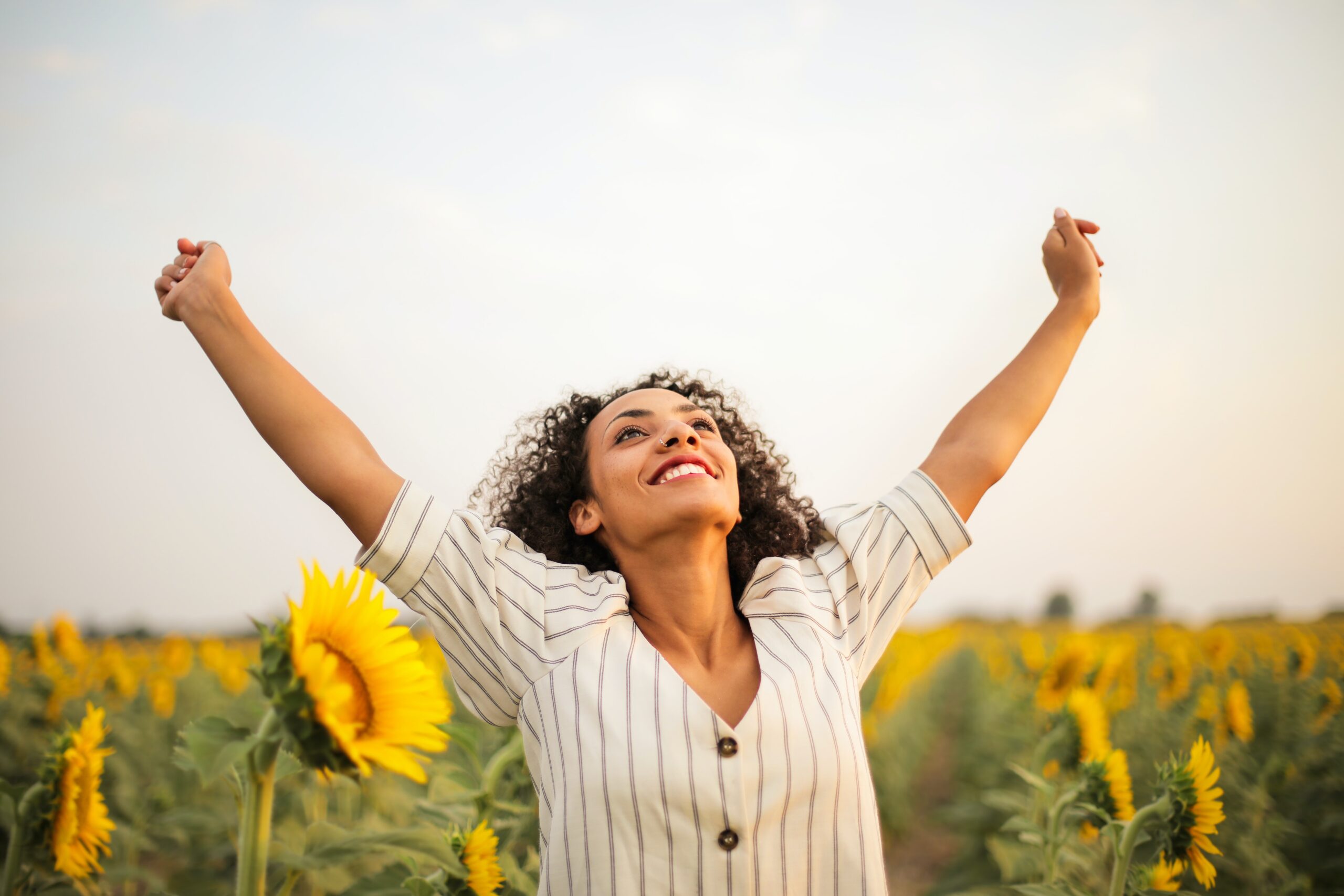 A happy woman runs through a field of sunflowers.